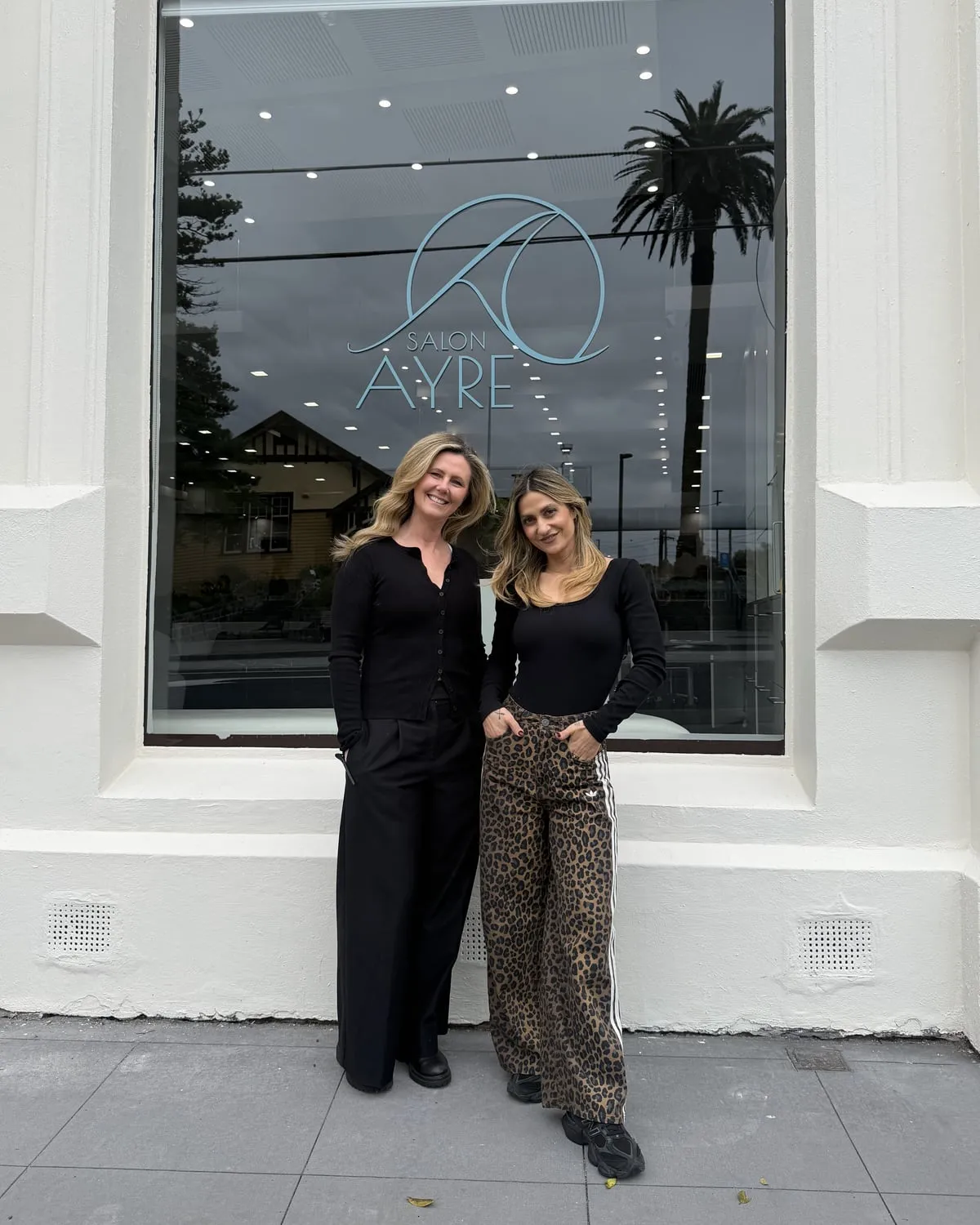 Emily and Sarah, co-founders of Salon Ayre, standing together outside the freshly painted boutique hair salon shopfront in Mentone VIC